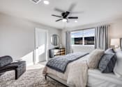 Thumbnail 15 of 47 - A bedroom with a bed, chair, and a ceiling fan.