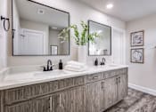 Thumbnail 18 of 47 - A bathroom with a large mirror and wooden cabinets.
