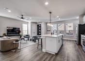 Thumbnail 6 of 47 - A modern kitchen with a white island and a living room with a sofa.