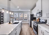 Thumbnail 11 of 47 - A modern kitchen with white cabinets and a black stove top oven.