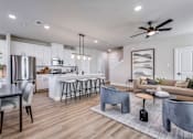 Thumbnail 1 of 47 - A modern kitchen with a dining table and a living room area.