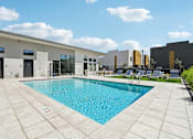 Thumbnail 35 of 45 - A pool surrounded by a patio and a building.