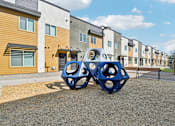 Thumbnail 20 of 20 - A playground with a blue structure in front of apartment buildings.