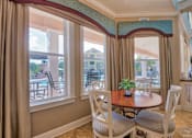 Thumbnail 24 of 32 - Pet-Friendly Apartments in Hinesville, GA – Tattersall Village - clubhouse seating area with table and chairs and view of the pool