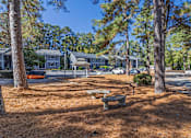Thumbnail 21 of 25 - A park with a bench and trees in front of a row of houses.