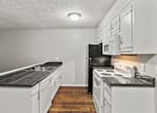 Thumbnail 3 of 25 - A kitchen with black appliances and white cabinets.