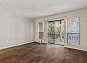 Thumbnail 14 of 25 - A room with wooden flooring and a sliding glass door leading to a balcony.