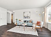 Thumbnail 14 of 47 - A living room with a grey couch, a white coffee table, and a painting on the wall.