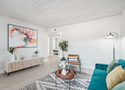 Thumbnail 6 of 34 - Two-Bedroom Apartments in North Mountain Village, Phoenix, AZ - Ardella on 28th - Bright Living Room With Teal Sofa, Accent Chair, Coffee Table Decor, Media Console, and Modern Wall Art.