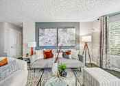 Thumbnail 10 of 34 - A living room with a grey couch and a large abstract painting on the wall.
