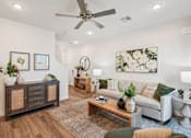 Thumbnail 7 of 45 - A living room with a white couch, a wooden coffee table, and a ceiling fan.