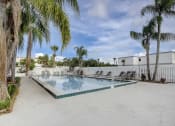 Thumbnail 10 of 15 - Derby Park Apartments in Daytona Beach, FL photo of the pool is surrounded by palm trees and a white fence