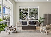 Thumbnail 26 of 31 - A living room with a large window and a view of trees and a building outside.
