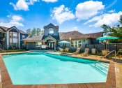 Thumbnail 2 of 20 - Pet-Friendly Apartments in Beaumont, TX – Breakwater Bay - swimming pool with umbrellas and beach chairs