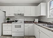 Thumbnail 3 of 23 - Element at 4411 Macon Apartments A white kitchen with a stove, sink, and cabinets.