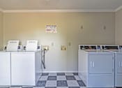 Thumbnail 2 of 23 - Element at 4411 Macon Apartments A laundry room with washers and dryers and a checkered floor.