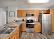 Thumbnail 1 of 28 - A kitchen with wooden cabinets and stainless steel appliances.