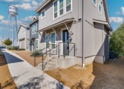 Thumbnail 36 of 40 - Apartments in Rowlett, TX - Village of Rowlett - Exterior View of Apartment Buildings with Concrete Stairs and Elevated Water Storage Tank in the Background