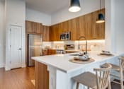 Thumbnail 1 of 28 - A kitchen with a white counter top and wooden cabinets.