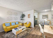 Thumbnail 1 of 46 - Pet-Friendly Apartments in Mesa, AZ - Mesa Station Apartments - Living Room With A Yellow Sofa, Matching Accent Chair, Coffee Table, Desk Area, and Dining Nook.