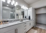 Thumbnail 10 of 34 - a bathroom with white cabinets and granite counter tops and a large mirror