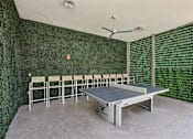 Thumbnail 15 of 31 - A ping pong table is in the middle of a room with a green wall.