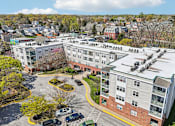 Thumbnail 32 of 32 - A large apartment complex with a parking lot in front.