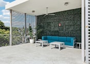 Thumbnail 13 of 31 - A blue couch is on a patio with a ceiling fan.