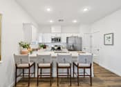 Thumbnail 6 of 45 - A kitchen with white cabinets and a white island with three chairs.