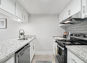 Thumbnail 1 of 34 - One Bedroom Apartments in North Mountain Village, Phoenix, AZ - Ardella on 28th - Kitchen with Wood-Style Flooring, Granite Countertops, Stainless Steel Appliances, and White Cabinetry.