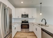 Thumbnail 3 of 56 -  Houses For Rent In Denton, TX - Carmel Villas - Kitchen With Modern Features, Soft Close White Cabinets and Drawers, Wood Vinyl Plank Flooring, Stainless Steel and Energy-Efficient Appliances, And Qu