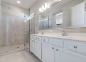 Thumbnail 13 of 19 - A	Luxury Two-Bedroom Homes for Rent in Houston, TX - East Heights - Bathroom with Double Vanity Sink, Shower, White Cabinets, and Mirror.