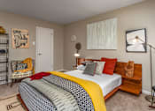 Thumbnail 29 of 34 - A bedroom with a bed, chair, and lamp.