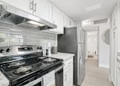 Thumbnail 2 of 34 - A kitchen with a black stove top oven and a black refrigerator.