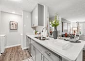 Thumbnail 1 of 34 - A modern kitchen with a white countertop and grey cabinets.
