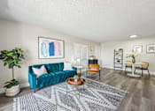Thumbnail 28 of 34 - A living room with a blue couch and a grey rug.