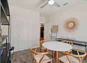 Thumbnail 10 of 39 - A white dining table with four chairs and a shelf with books and decorative items.