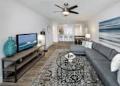 Thumbnail 6 of 28 - A living room with a grey couch, a coffee table, and a television.