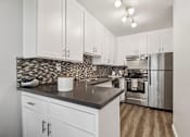 Thumbnail 3 of 32 - A kitchen with white cabinets and a black countertop.