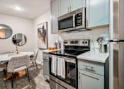 Thumbnail 3 of 34 - A modern kitchen with a stove top oven and microwave.