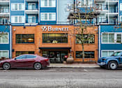 Thumbnail 16 of 16 - A red car is parked in front of a building with the sign 95 Burnett.