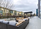 Thumbnail 14 of 16 - A rooftop patio with a black railing and a white couch.