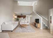 Thumbnail 3 of 51 - A living room with a white couch and a wooden coffee table.