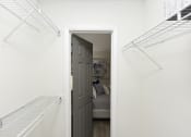 Thumbnail 14 of 27 - a white closet with white shelves and a door open to a room with a couch