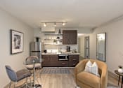 Thumbnail 12 of 51 - A modern kitchen with a glass table and a brown armchair.