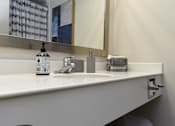 Thumbnail 14 of 51 - A white sink with a soap dispenser and a mirror above it.