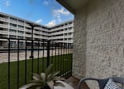 Thumbnail 18 of 51 - A balcony with a chair and a plant in front of a building.