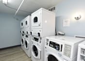Thumbnail 25 of 51 - A stack of white front load washing machines in a laundromat.