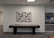 Thumbnail 19 of 51 - A black pool table in a room with a white wall and a painting above it.