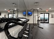 Thumbnail 28 of 51 - A gym with a row of dumbbells and two treadmills.